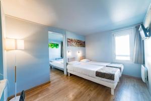 马孔Brit Hotel Macon Nord Autoroute du Soleil的一间卧室设有两张床和窗户。