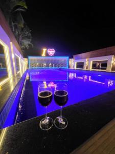 罗纳瓦拉THE PERFECT STAYS: CHOUDHARY VILLA的两杯酒坐在游泳池旁的桌子上