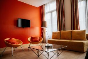 图尔奈阿尔坎塔拉酒店的客厅拥有橙色的墙壁,配有沙发和椅子