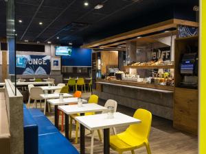 土伦Ibis Budget Toulon Centre的餐厅设有桌子、黄色椅子和柜台