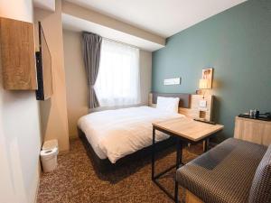 高松Comfort Hotel Takamatsu的一间卧室配有一张床、一张桌子和一个窗户。