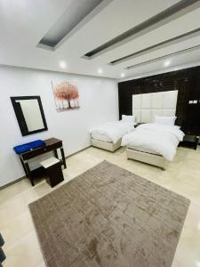 Al Nairyah沙漠棕榈公寓式酒店的一间卧室配有两张床、一张桌子和一面镜子