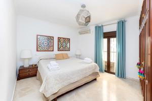 格拉纳达CASA SAN MATIAS的白色卧室配有床和蓝色窗帘