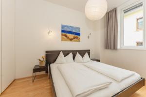 斯拉德明Appartements Tamino by Schladming-Appartements的一间卧室配有一张带白色床单的床和一扇窗户。
