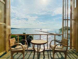 格兰岛เรือนตะวัน เกาะล้าน RueanTawan Kohlarn的阳台配有桌椅,享有水景。