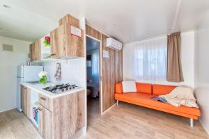 佩斯基耶拉德加达San Benedetto Camping Relais的小厨房配有橙色沙发和炉灶