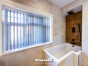 莱斯特Stunning 5bdr Detached King Suite Abode的带浴缸的浴室和大窗户