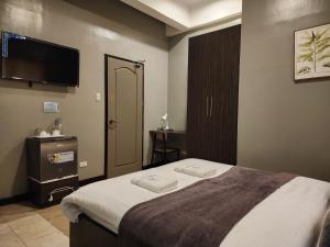 大雅台Grayhouse Inn Tagaytay的一间卧室配有一张床和一台平面电视