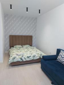 阿拉木图ЖК Palladium/41的一间卧室配有一张床和一张蓝色的沙发