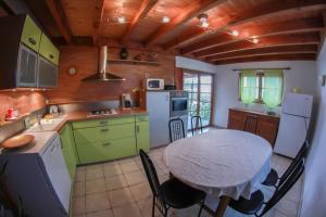 La PirrazAppartement en duplex dans chalet à Talloires的一间带桌子的厨房和一间带绿色橱柜的厨房