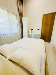 清莱HomeHug@ChiangRai的一间卧室设有两张白色的床和窗户