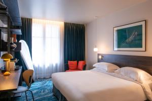 巴黎金色郁金香诺阿伊剧院酒店的酒店客房设有一张大床和一张书桌。