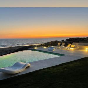萨阿拉德洛斯阿图内斯Playa Blanca Zahara的一个带椅子的游泳池,日落时分享有海景