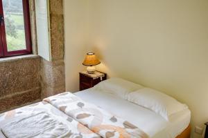 塞亚Quinta da Cerdeira的一间卧室配有一张床和一张带台灯的桌子