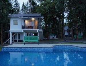 PadinjaratharaMisty Dam Wayanad Premium Resort With Banasura Dam View的游泳池旁带绿色长凳的房子