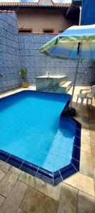 蒙加瓜Casa Mongagua的蓝色的游泳池,配有遮阳伞和桌子