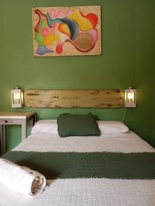 伊瓜苏港Ára apart的绿色卧室内的一张床铺,墙上有绘画作品