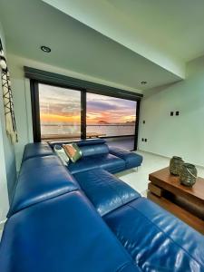 马萨特兰Altomare Seaview的客厅设有蓝色皮革沙发和大窗户
