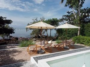 象岛内斯特森斯度假酒店的一个带椅子和遮阳伞的庭院和一个游泳池