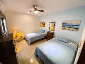 女人岛CASA AROMA DE MAR的一间卧室配有两张床和吊扇