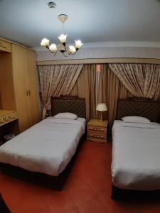艾因苏赫纳Porto Elsokhna pyramids Family的一间卧室配有两张床和吊灯。