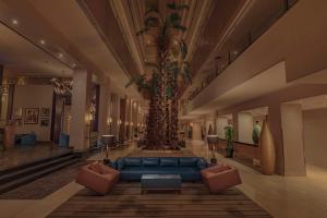 开罗开罗赫利奥波利斯丽笙布鲁酒店的大堂设有蓝色的沙发和棕榈树