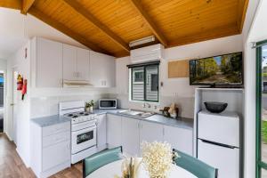 吉朗Tasman Holiday Parks - Geelong的厨房配有白色橱柜和木制天花板