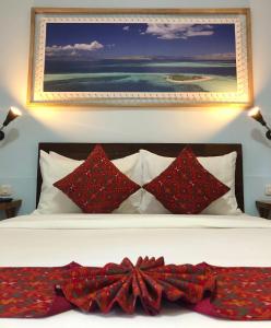 纳闽巴霍维莫拉斯宾馆的一张带红色枕头的床和墙上的绘画