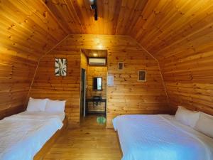 Kon Von KlaT'MĂNG ĐEENG HOMESTAY的小木屋内一间卧室,配有两张床
