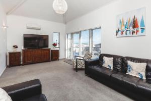 新普利茅斯Holiday On Hamblyn的客厅配有黑色真皮沙发和平面电视。