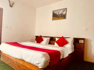 马拉里Hotel Alpine的一间卧室配有两张带红白色枕头的床