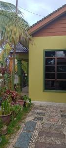 瓜拉丁加奴HIJRAH FLEKSI HOMESTAY的一座黄色房子,前面有一棵棕榈树