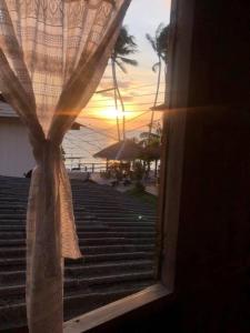 塔林甘海滩Aforetime House @ Samui的透过窗帘的窗户可欣赏到日落美景
