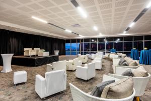 波哥大波哥大机场万怡酒店的一间设有白色椅子和桌子及窗户的房间