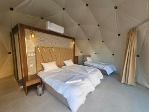 瓦迪拉姆غرووب وادي رم的一间帐篷内带两张床的卧室