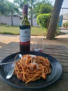 阿格拉Backpackers Village Agra的桌上的一块意大利面和一瓶葡萄酒