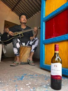 阿格拉Backpackers Village Agra的弹吉他和一瓶葡萄酒的人