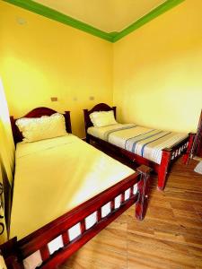RubiriziLights of kazinga orphanage and homestay的配有黄色墙壁和木地板的客房内的两张床