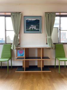 日光今市STAY - NIKKO private house rental only 5 min to station的一间设有两张绿色椅子和一张书桌的等候室