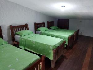 奥林达Casa Prudente的带三张床和绿色床单的客房