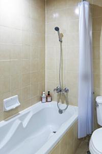 曼谷拉维法公寓的带浴缸、卫生间和淋浴的浴室。