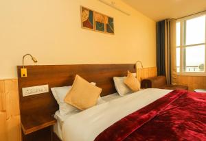 达兰萨拉Himalayan Suite的一间卧室配有一张带红色毯子的大床