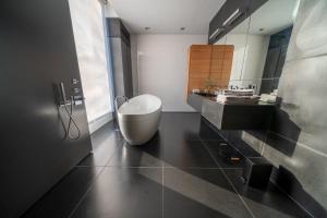 博克斯特尔Bed & Wellness Boxtel, luxe kamer met airco en eigen badkamer, ligbad的浴室配有白色浴缸和水槽