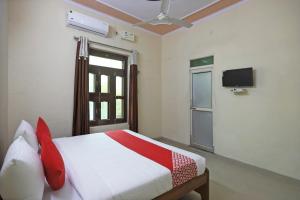 MahendragarhOYO 62761 Hotel Daksh的卧室配有一张床,墙上配有电视。