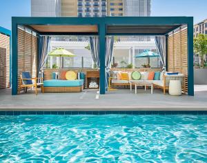 圣地亚哥Margaritaville Hotel San Diego Gaslamp Quarter的庭院设有游泳池、椅子和桌子。