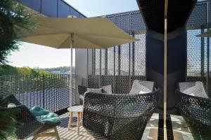 卢森堡Rise - Penthouse Suite with Terrace的阳台的天井配有椅子和遮阳伞。