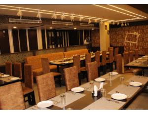 占西Hotel Bundelkhand Pride, Jhansi的餐厅设有长桌、桌椅和椅子