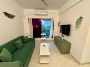 孟买La Olive 1 BHK Service Apartment的客厅配有绿色沙发和桌子