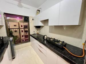 孟买La Olive 1 BHK Service Apartment的厨房配有白色橱柜和黑色台面