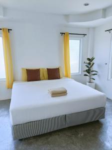 格兰岛Thongtalay Bed & Breakfast Koh Larn的白色的白色客房内的一张大白色床,配有黄色窗帘